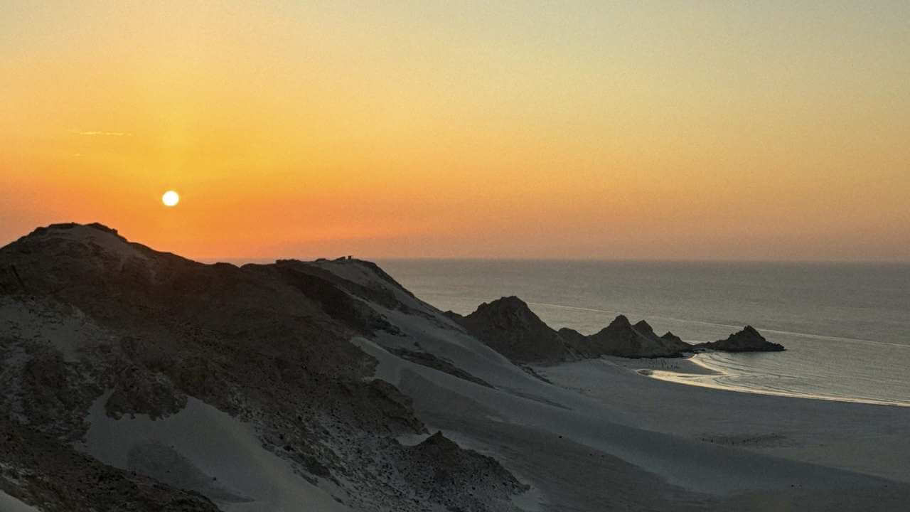 the sun is setting over the sand dunes in the desert