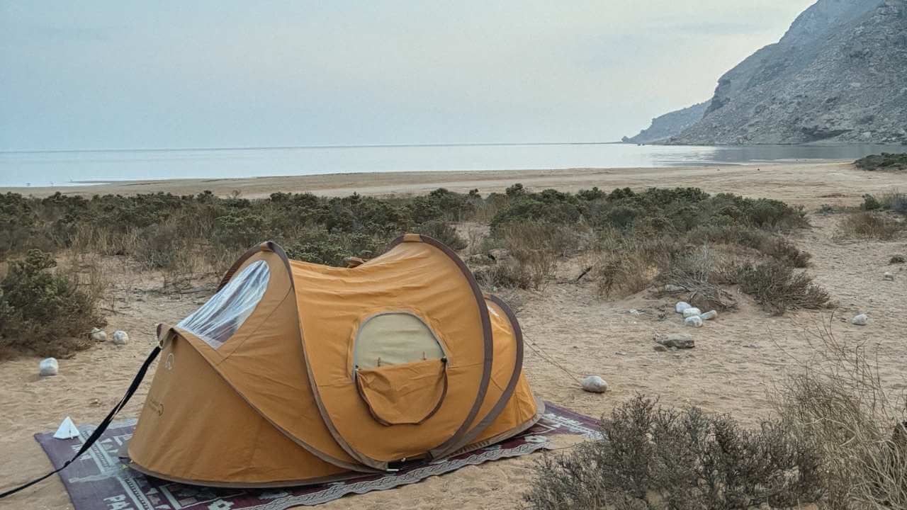 a tent is set up on the beach near a body of water