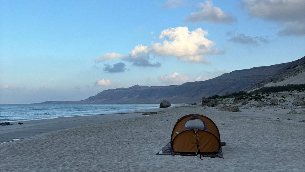 a tent is set up on the beach next to the ocean