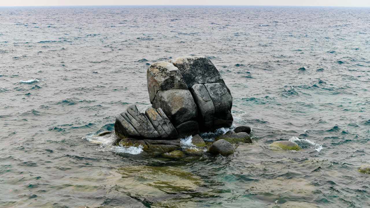 a large rock in the middle of the ocean