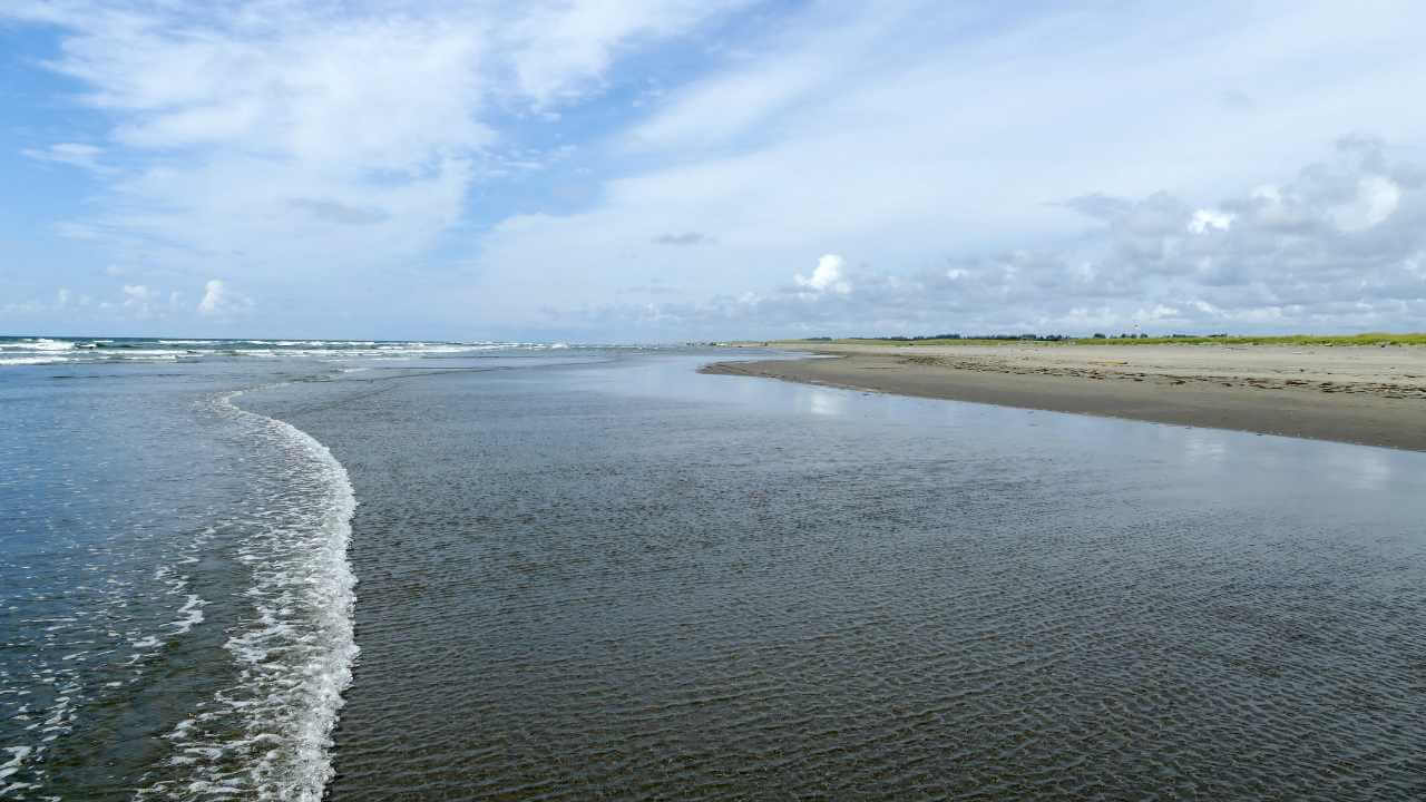 a sandy beach with waves coming in and out of the water