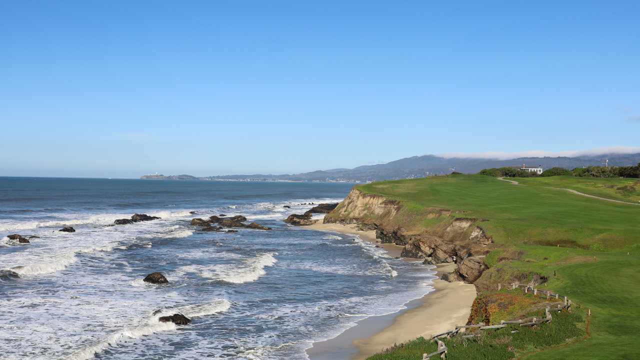 a view of the ocean and golf course from the top of a hill