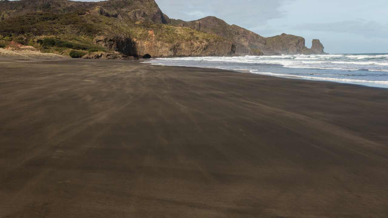 a black sand beach with mountains in the background