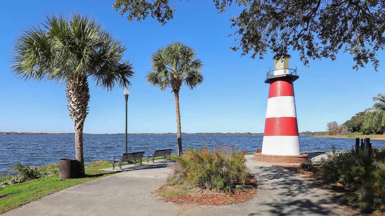 a red and white lighthouse stands in front of a body of water