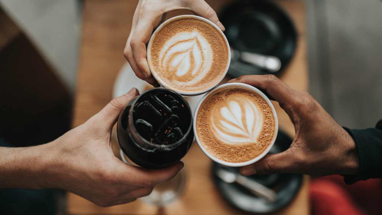 two people toasting coffee in their hands