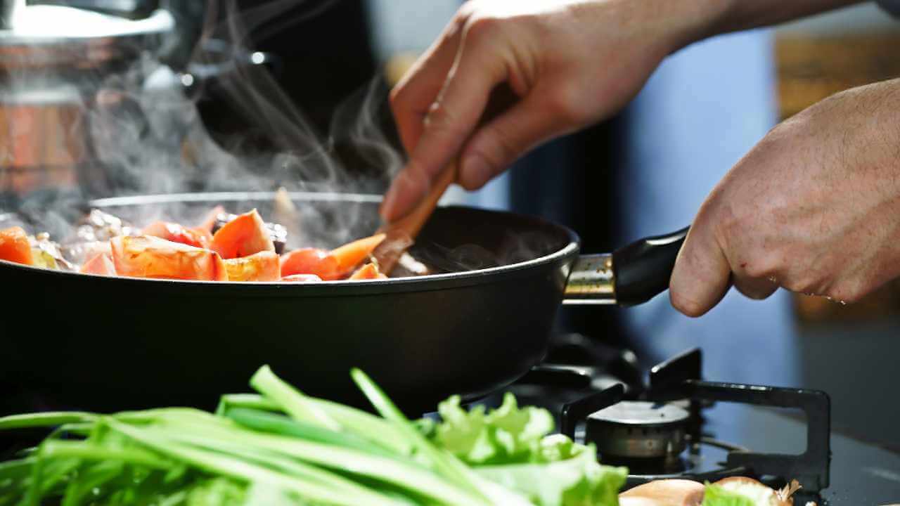 a person is cooking vegetables in a pan on a stove