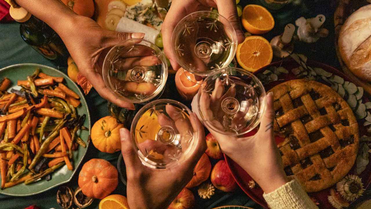 a group of people toasting with wine glasses over a table full of food