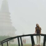 a person standing on a bridge in front of a pagoda