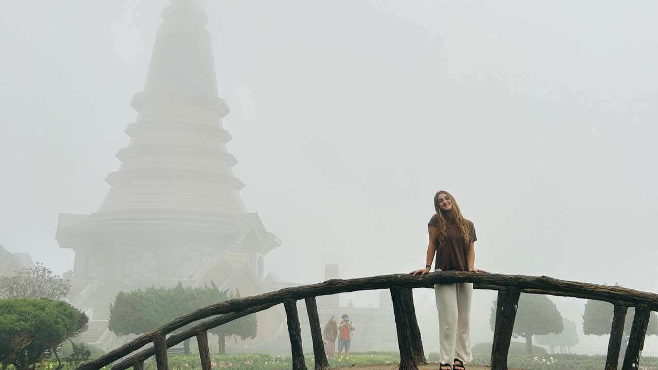 a person standing on a bridge in front of a pagoda