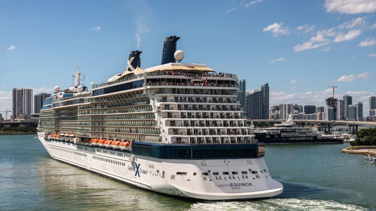 a large cruise ship in the water with a city in the background