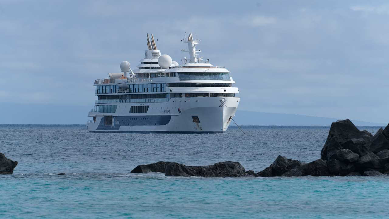 a cruise ship in the ocean near some rocks