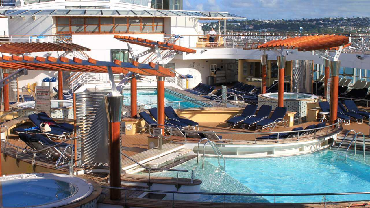 a large pool on a cruise ship with lounge chairs and umbrellas