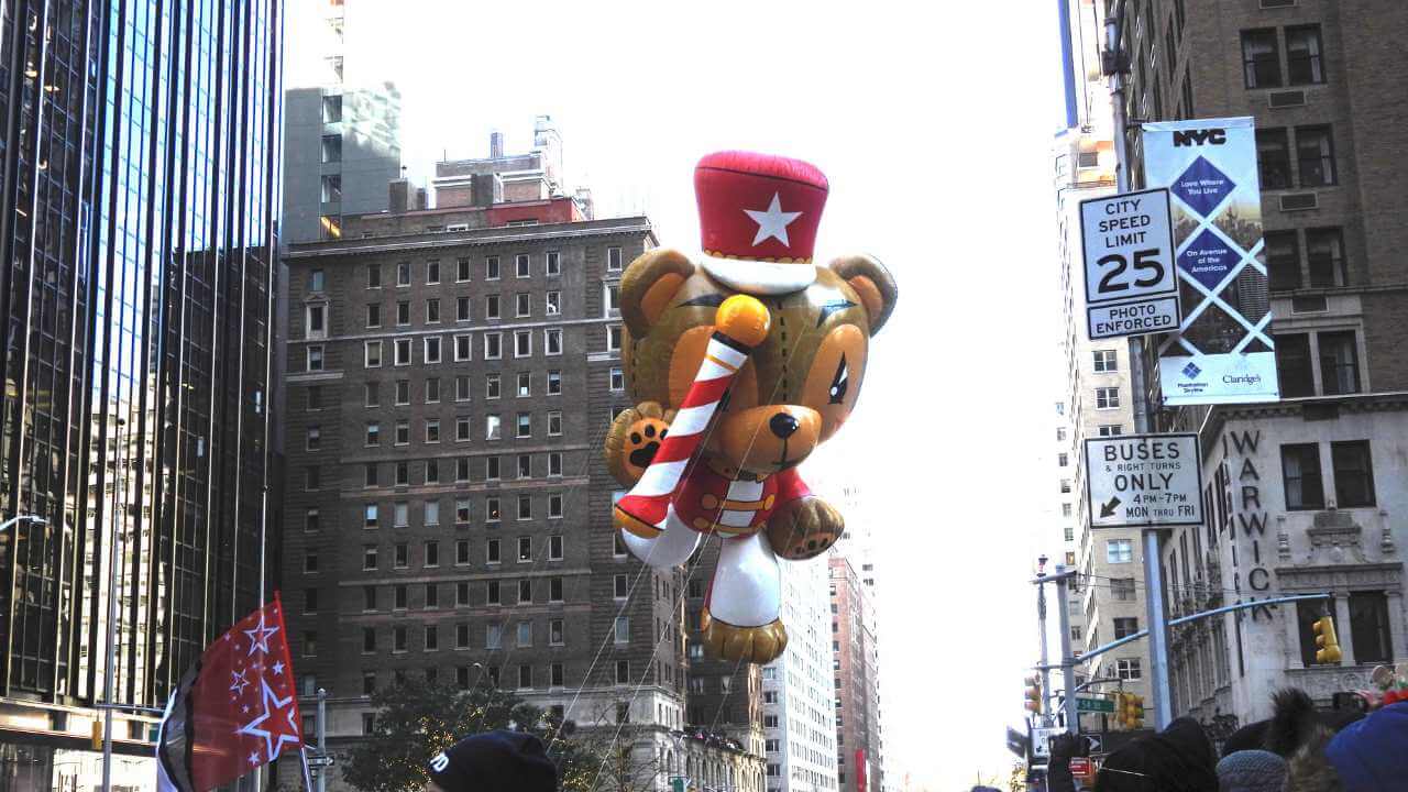 a large balloon with a teddy bear on it in the middle of a city street