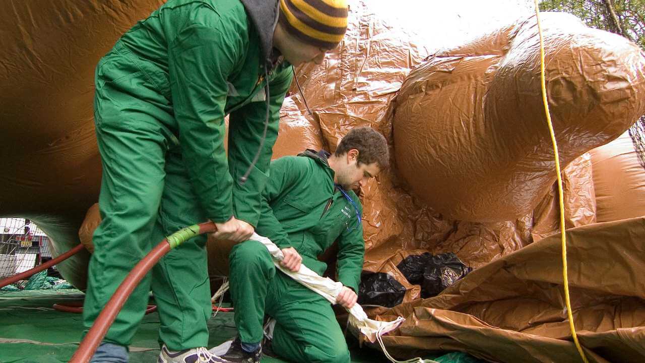 Two people are working on an inflatable animal.