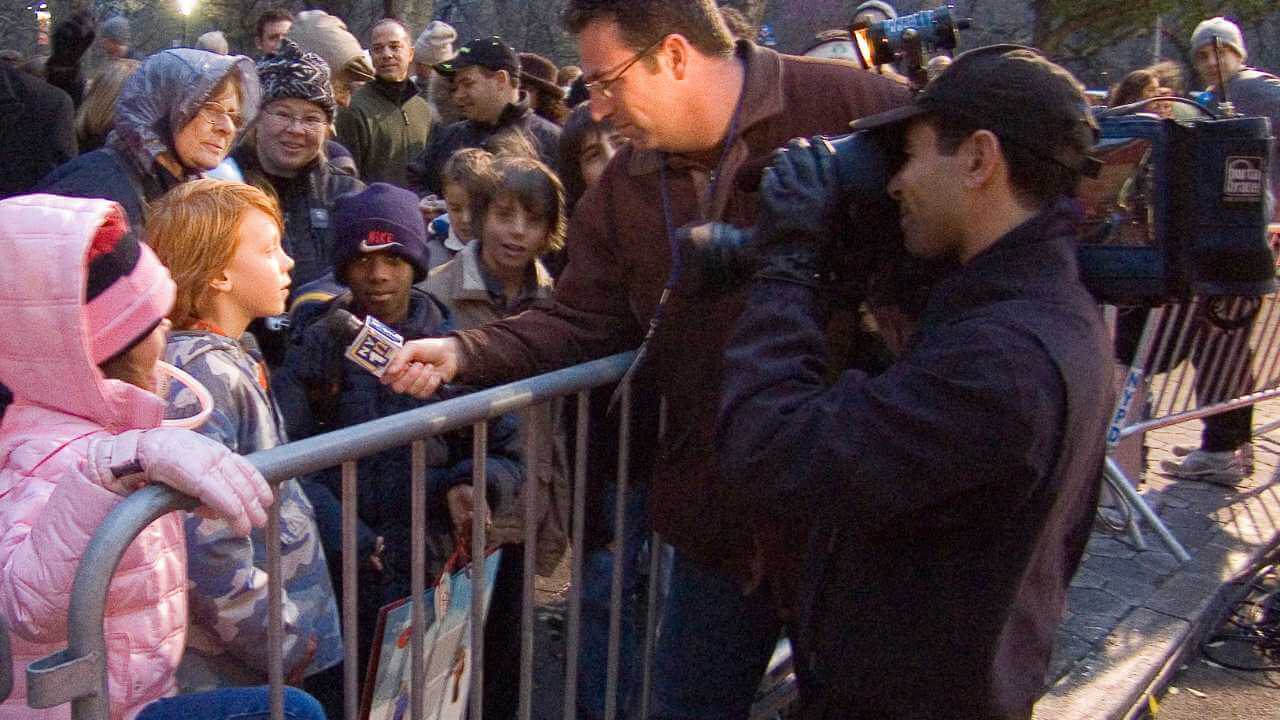 a person is talking to a young person in front of a crowd