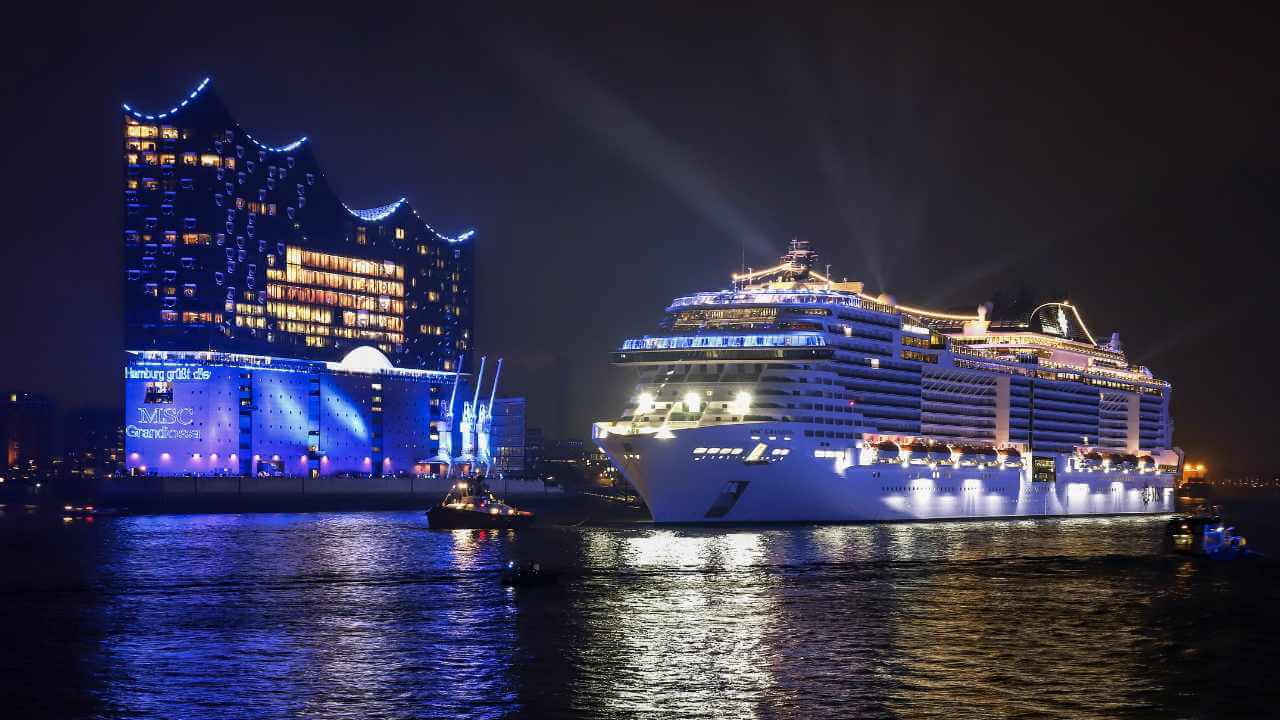 a cruise ship is docked in front of a building at night