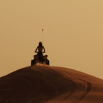 a person riding an atv on top of a sand dune