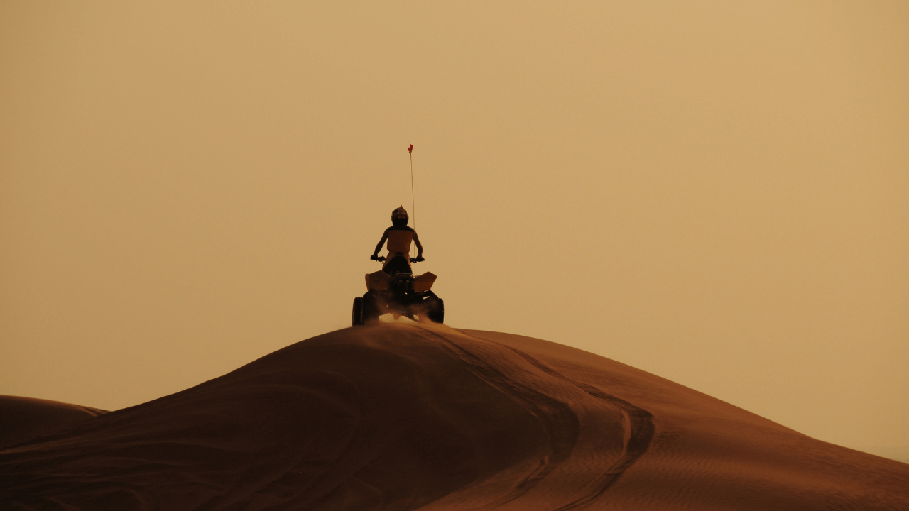 a person riding an atv on top of a sand dune