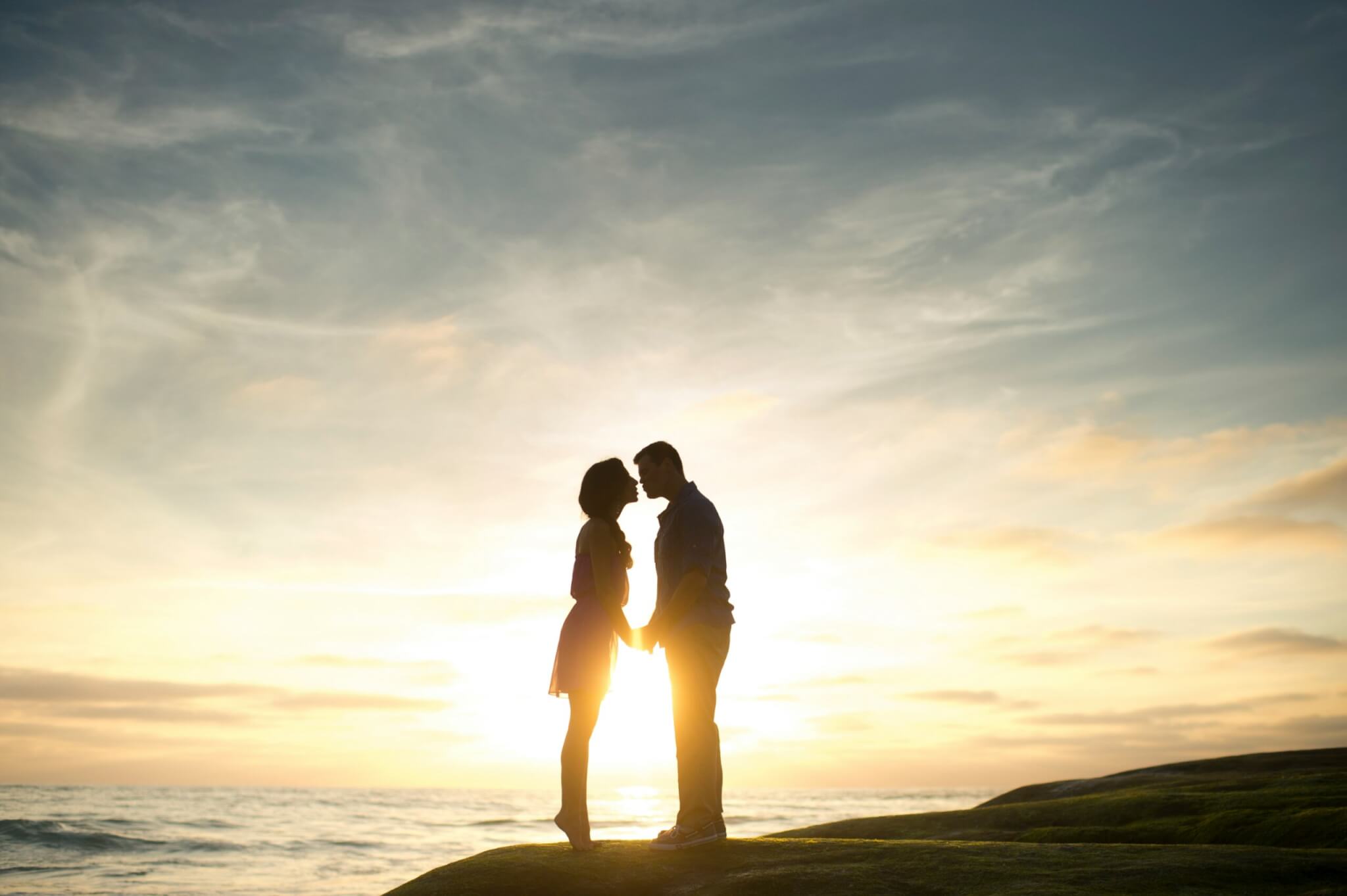 two people about to kiss with the sunset in the background