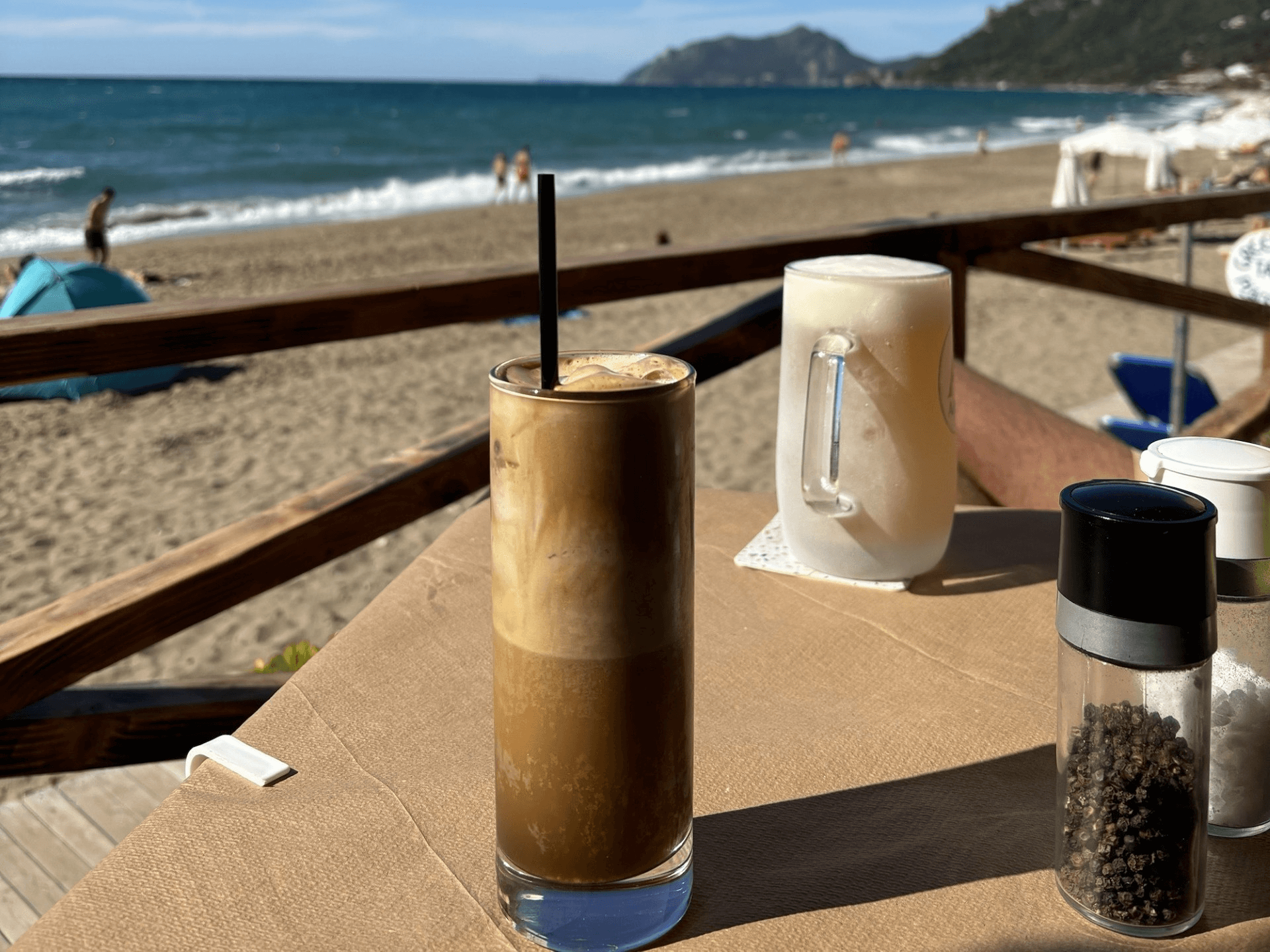 tall glass of coffee with ocean in the background