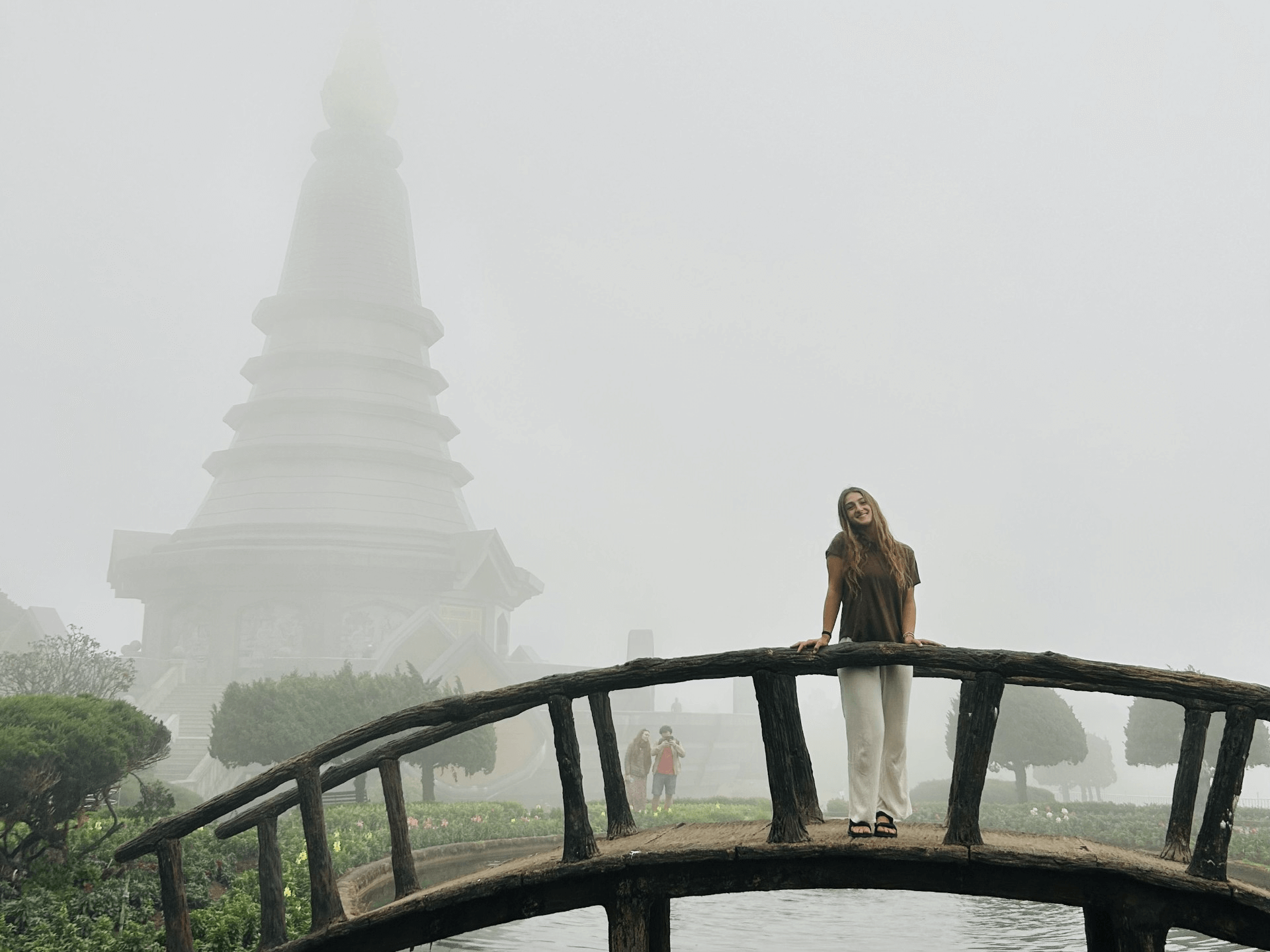 a person standing on a bridge in front of a pagoda