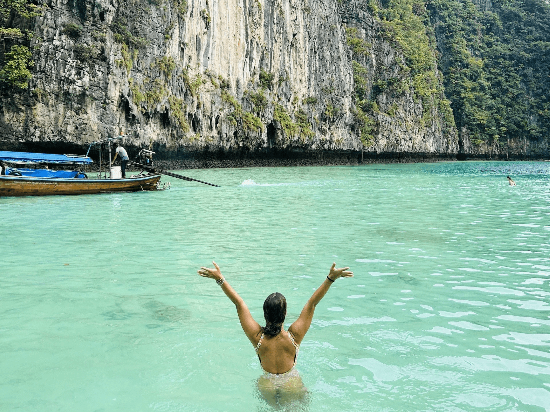 person in blue water with their hands in the air