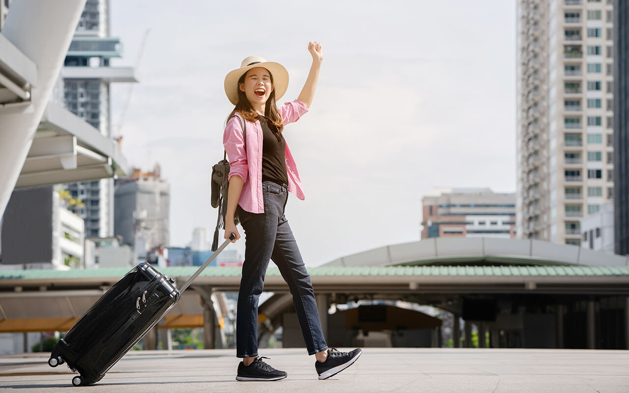 Tourist walking on city street and carrying a suitcase 