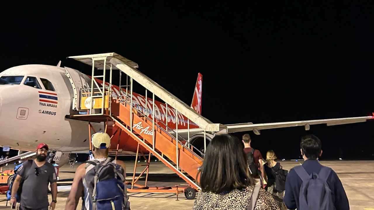 a group of people boarding an airplane at night