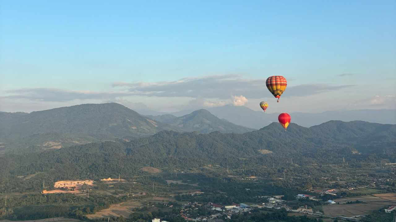 a group of hot air balloons flying over the mountains