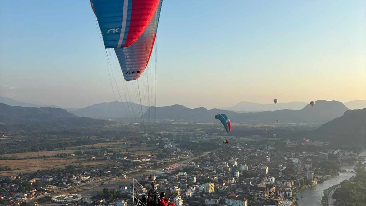 paragliders flying over a city with mountains in the background