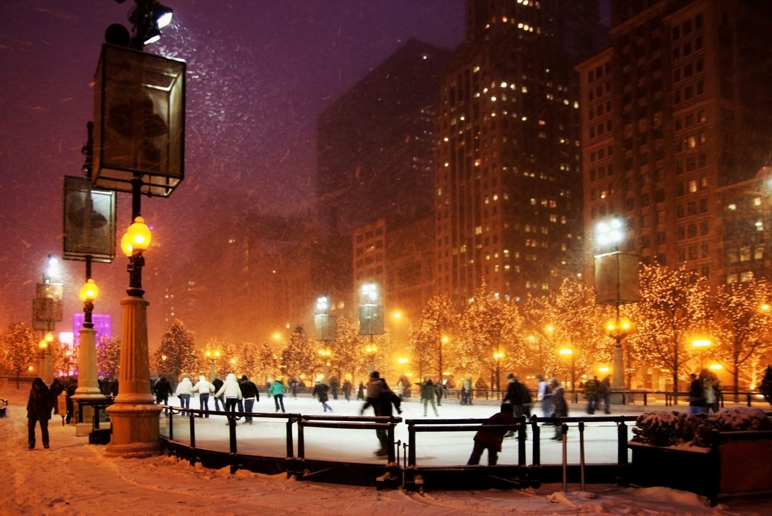 Winter night in Chicago. People enjoying ice skating at Millennium park ice rink during snowy night in Chicago.
