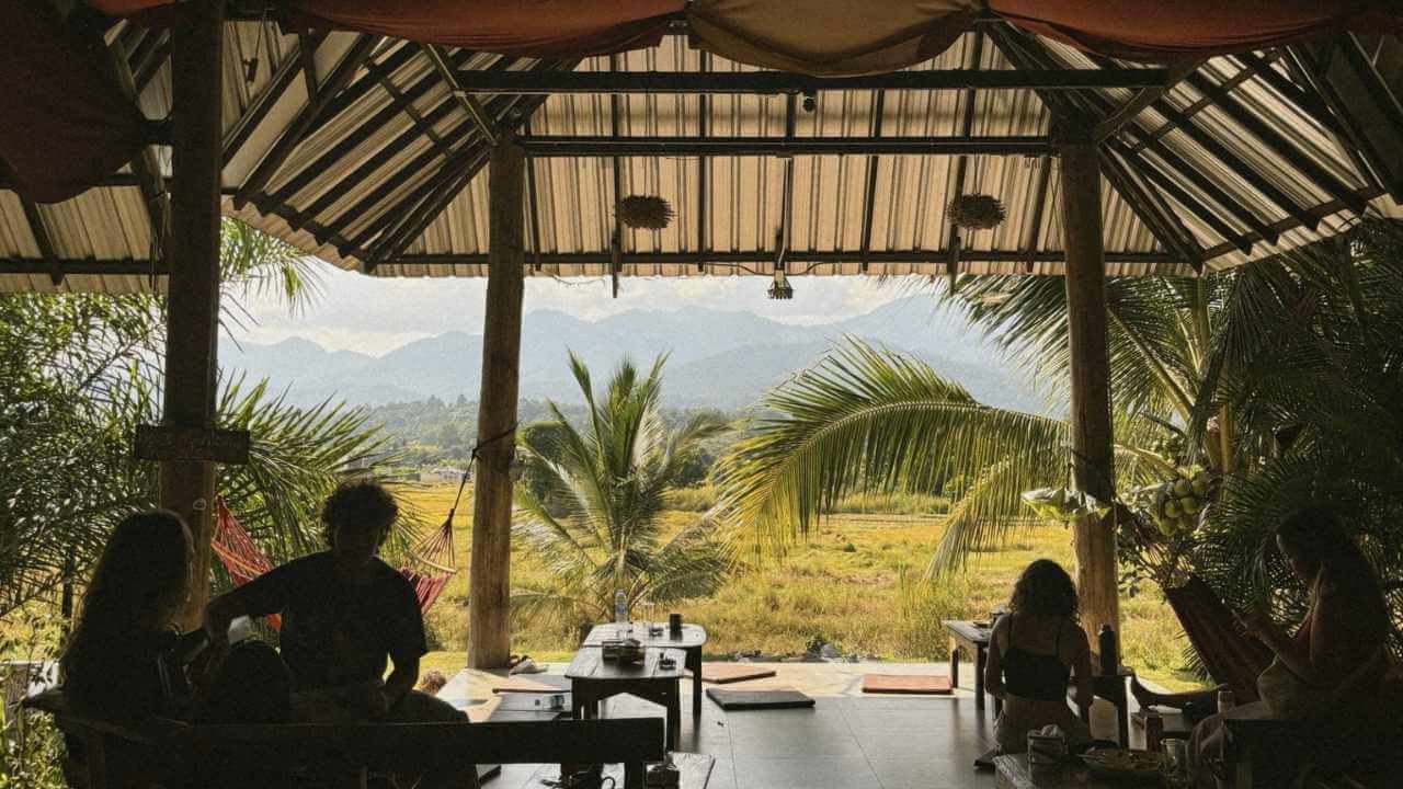 a group of people sitting at tables in a restaurant with mountains in the background