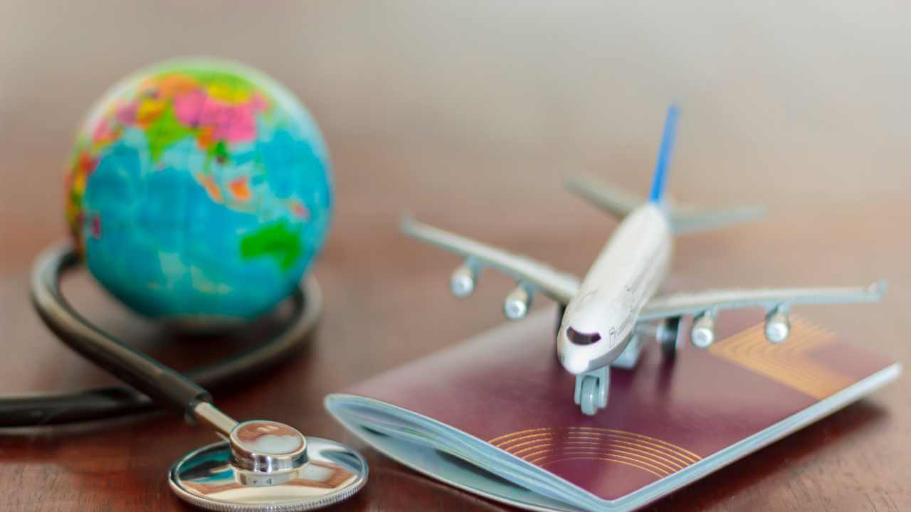 airplane, passport and stethoscope on wooden table