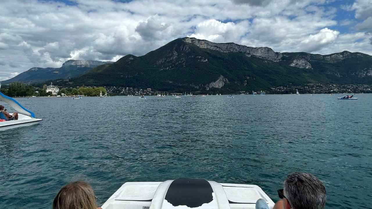 a group of people on a boat in the water with mountains in the background