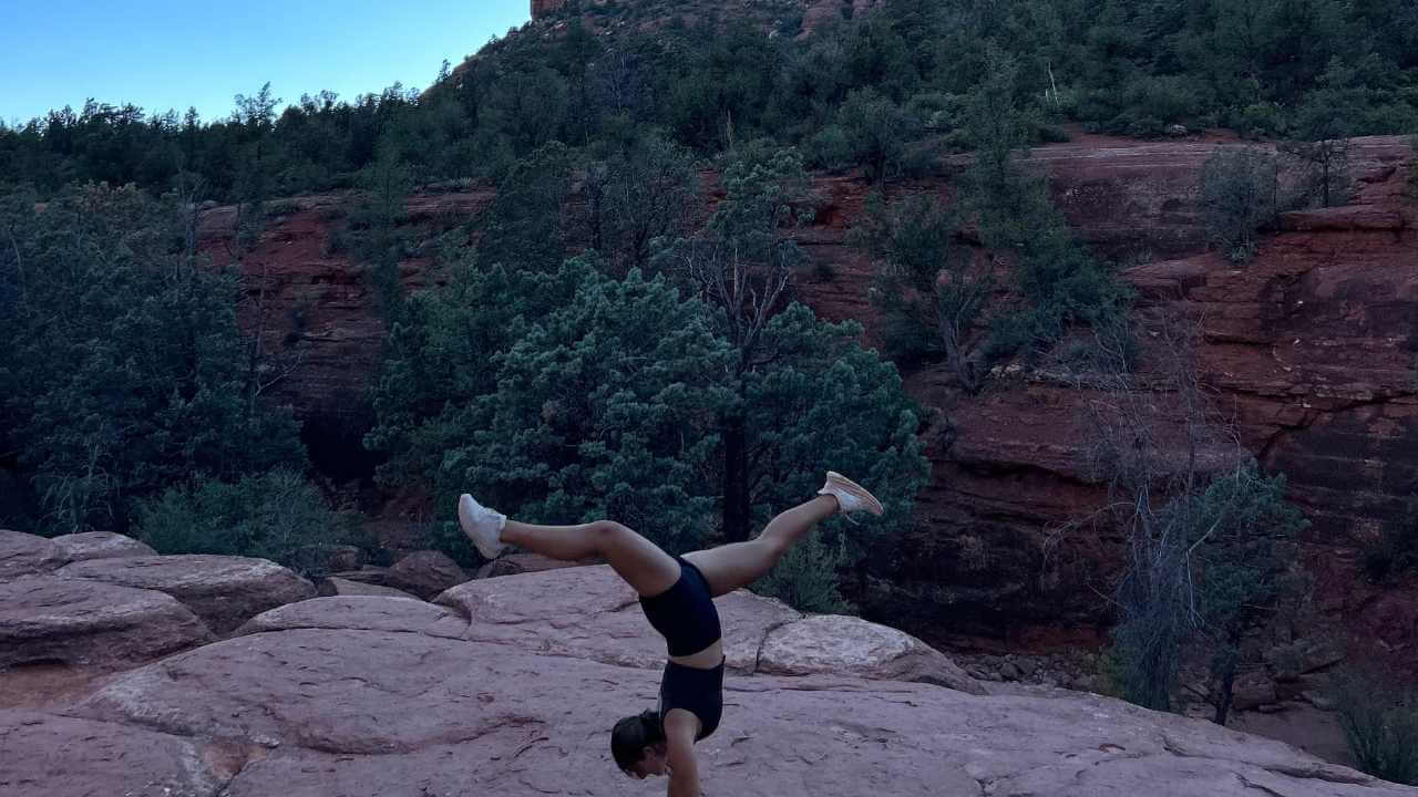 a person doing a handstand on a rock in front of a mountain