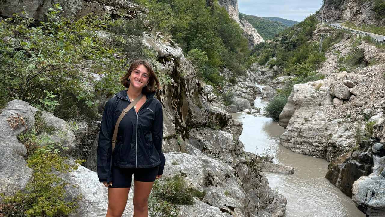 a person standing in front of a river in the mountains