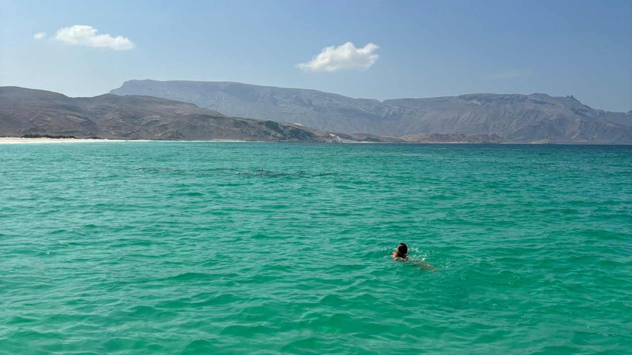 a person swimming in the ocean with mountains in the background