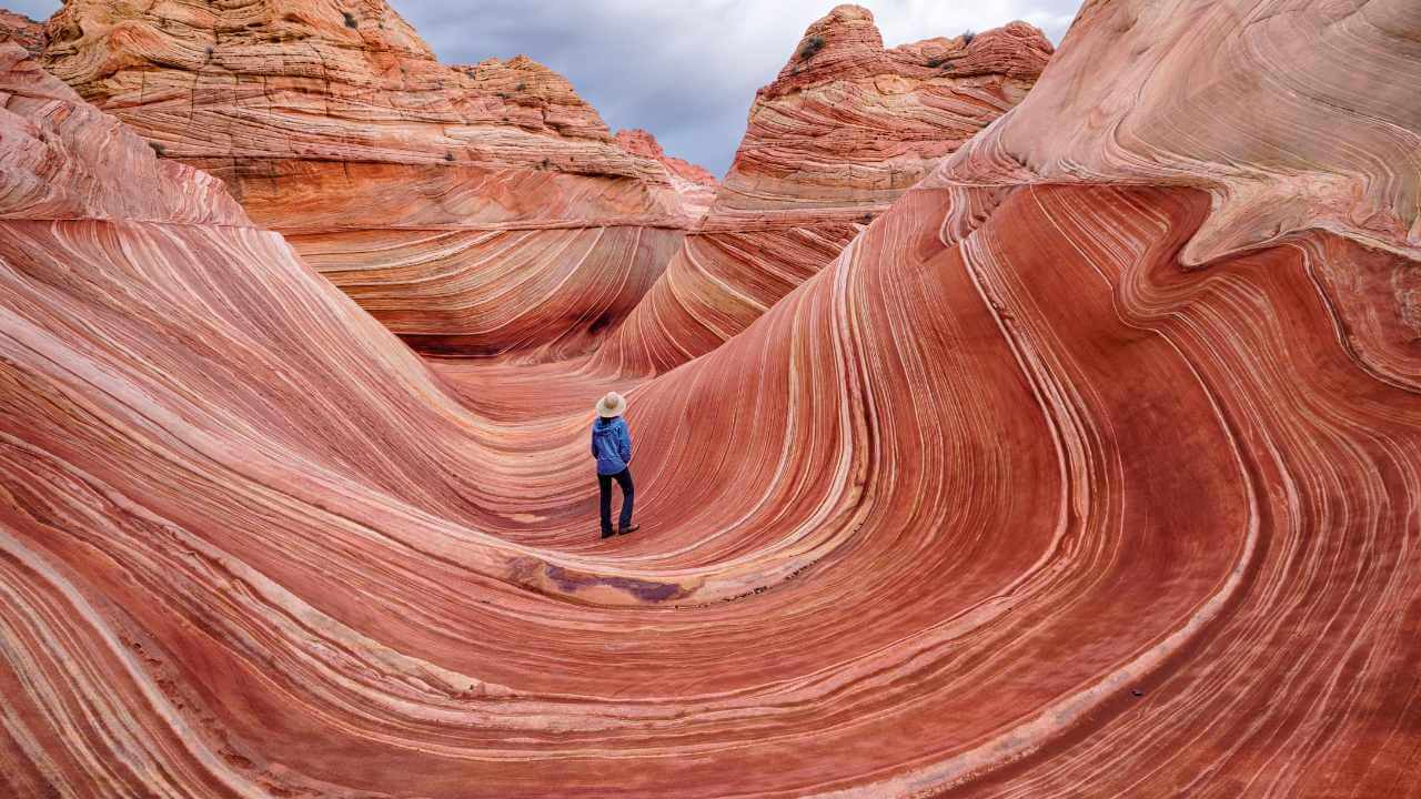 a person standing in the middle of a wave of red rock