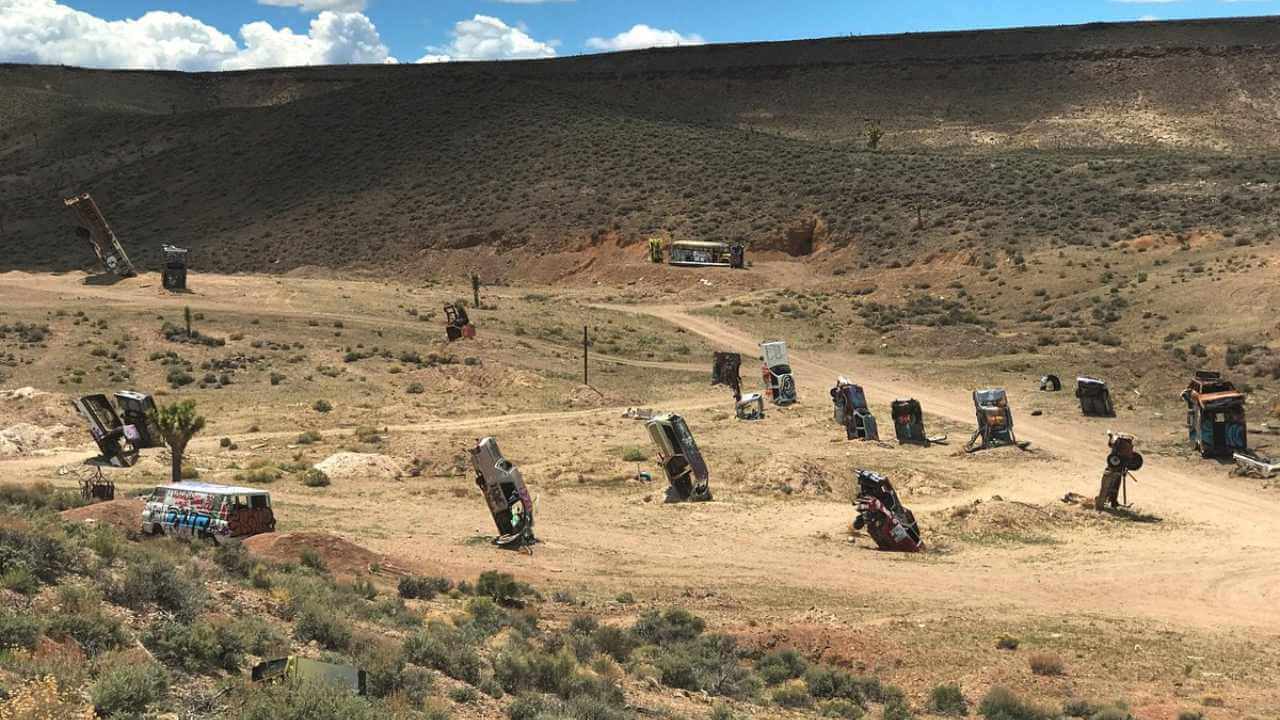 a group of cars in the desert with mountains in the background