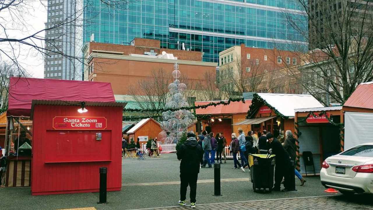 Several people are standing in front of a Christmas market.