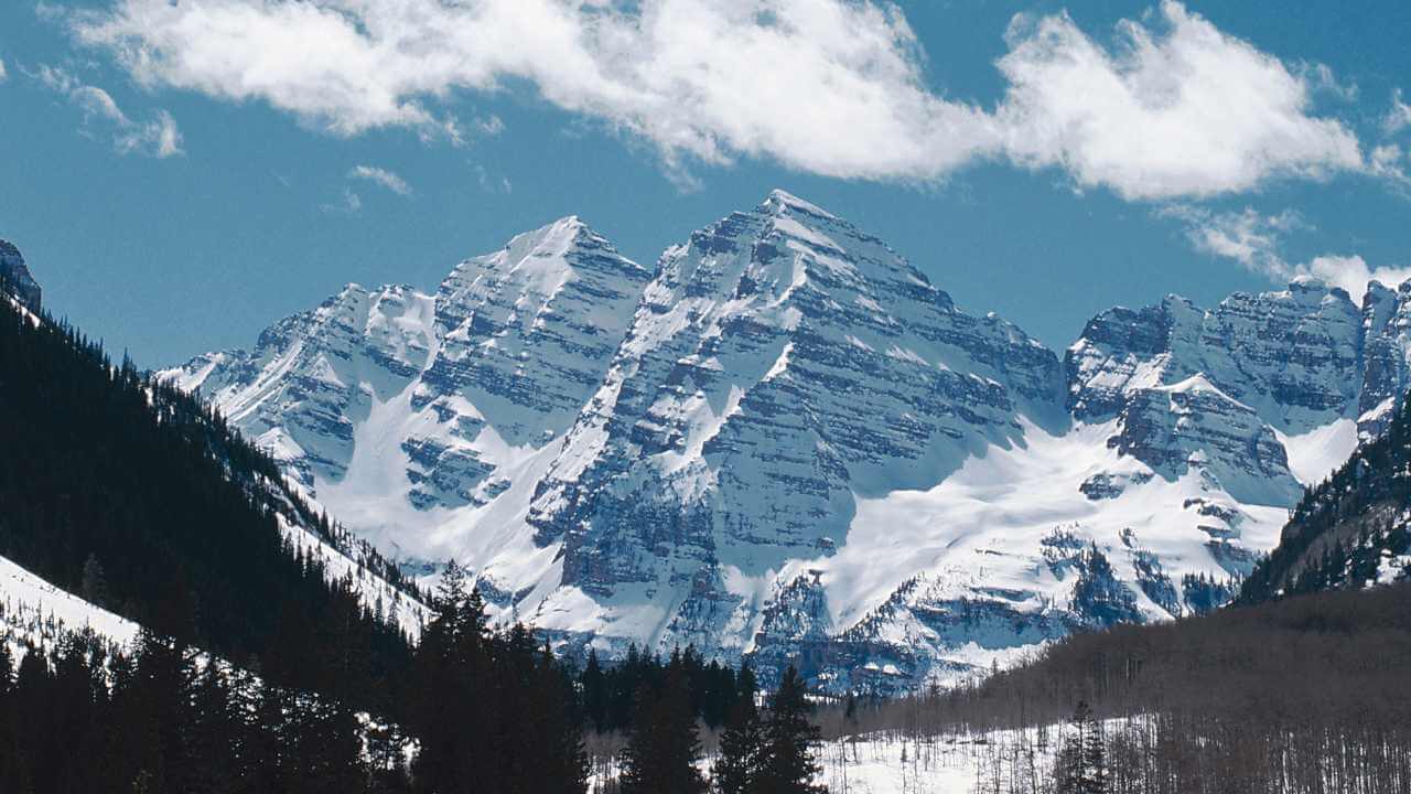 a snowy mountain range with trees and snow on the ground