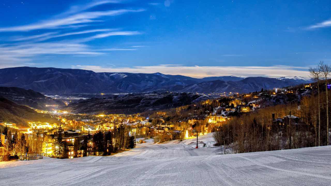 a ski resort at night with lights on the slopes