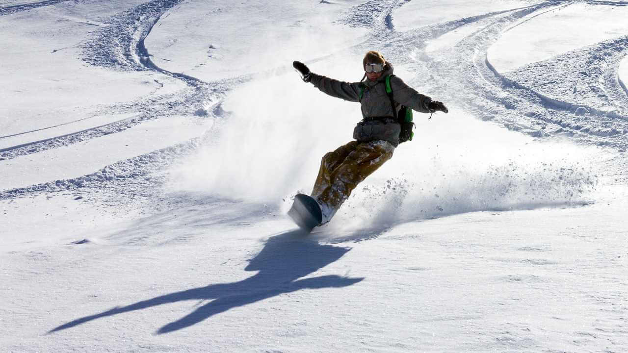 a person riding a snowboard down a snow covered slope