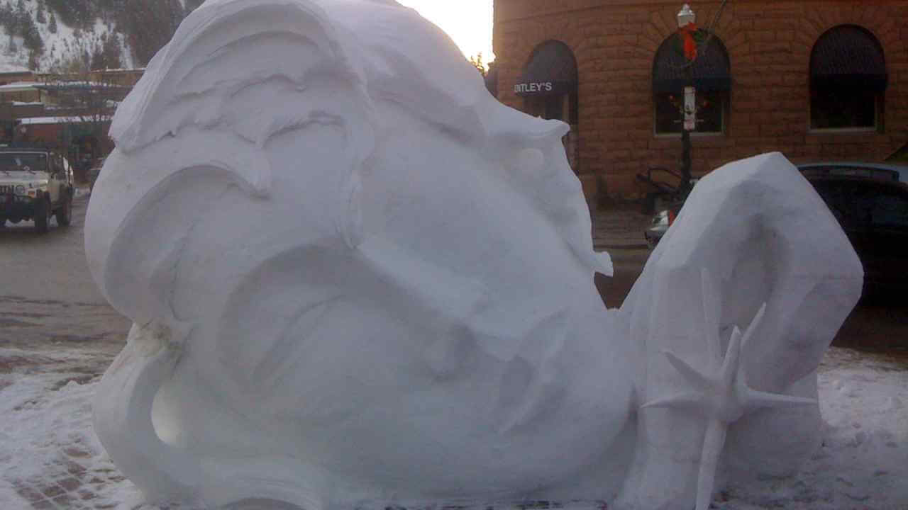 a snow sculpture of a face on the side of the road