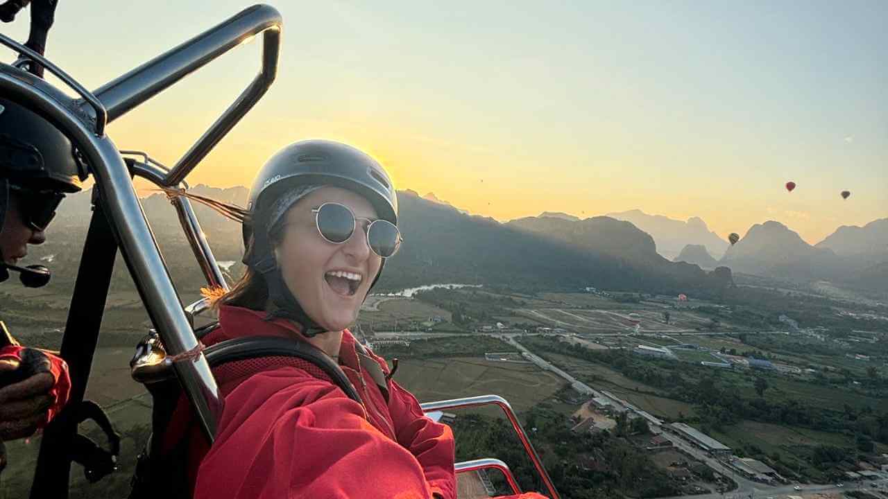 two people are riding in a hot air balloon at sunset