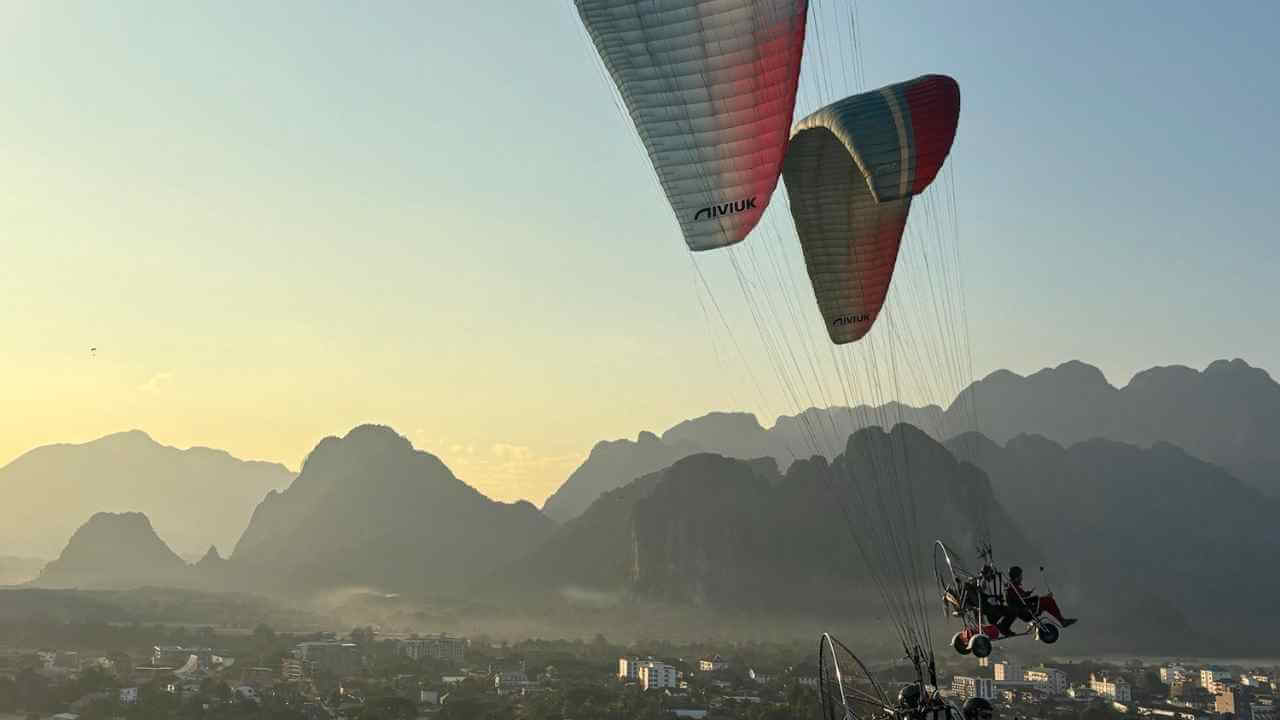 two paragliders are flying over a mountain range