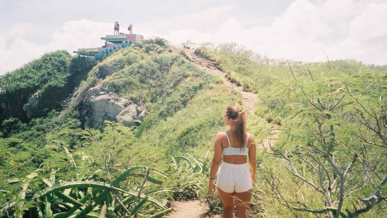 a person in white shorts and white tank top walking up a hill