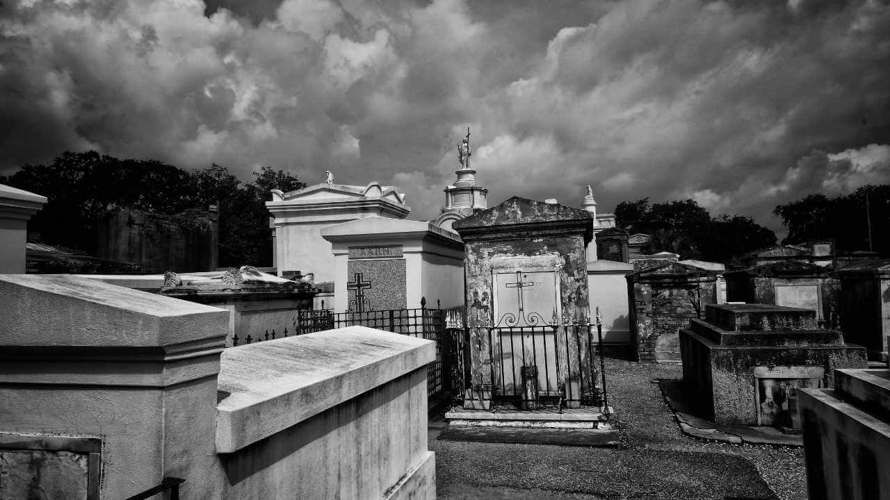 a black and white photo of a cemetery under a cloudy sky