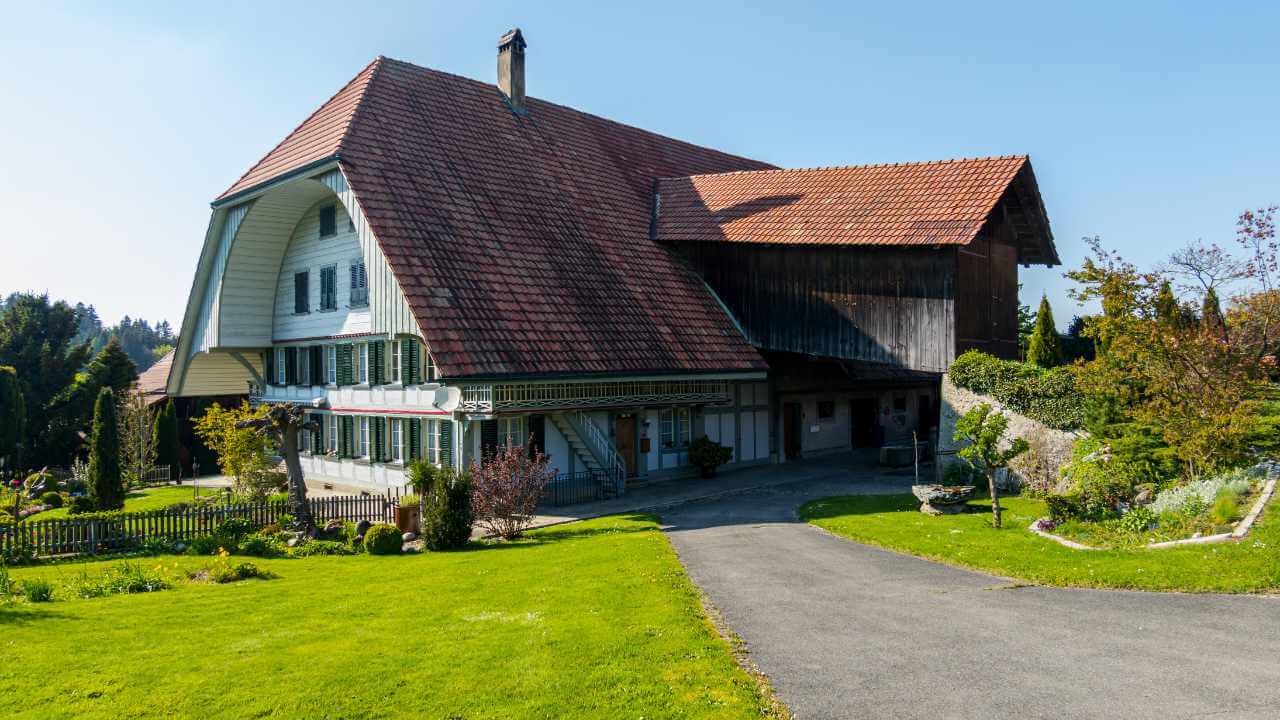 a large house with a red roof in the middle of a lush green field
