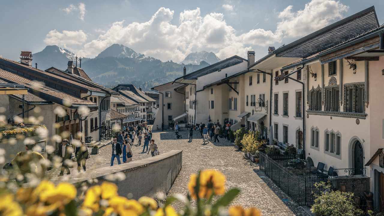a narrow cobblestone street with yellow flowers in front of buildings
